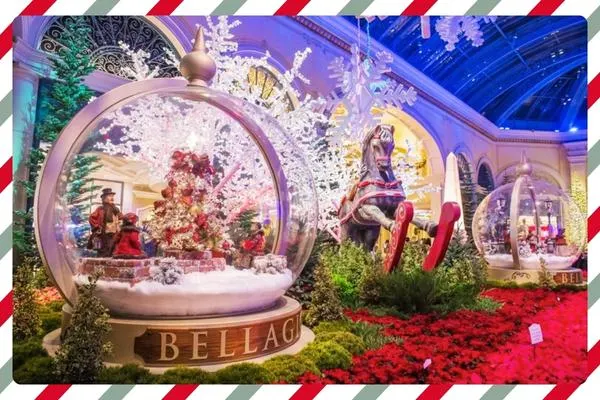 festive holiday scene at bellagio conservatory in las vegas with snow globes ornaments poinsettias and rocking horse under glass ceiling