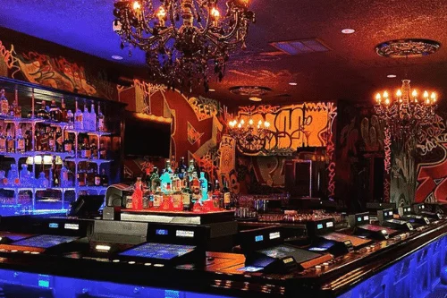 interior of las vegas dive bar with graffiti walls illuminated bar counter video poker screens and eclectic decor