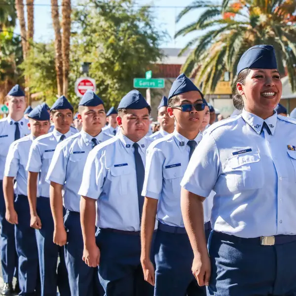 uniformed cadets marching in formation during downtown las vegas veterans day parade with palm trees and city signs in background