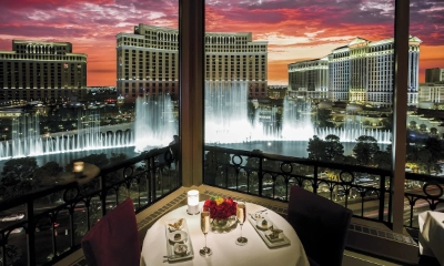 romantic table setting at eiffel tower restaurant las vegas with bellagio fountain view and red roses