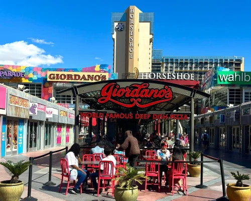 the second level of the Grand Bazaar shops outdoor dining wahlburgers Giordano's restaurants and the horseshoe hotel in the distance on a sunny day in Las vegas