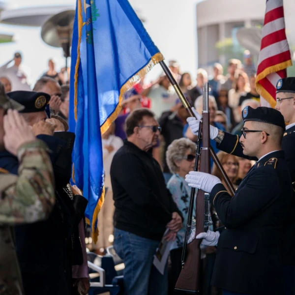 military color guard presenting flags during henderson veterans day ceremony at water street plaza with crowd saluting