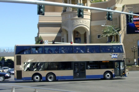 The Deuce double decker bus operated by RTC turns onto the Las Vegas Strip near a palm-lined resort showcasing affordable public transit for tourists and locals