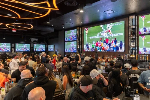 a lively crowd of sports fans watch a football game at an upscale sports bar in las vegas