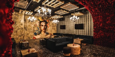 stylish speakeasy-style lounge in las vegas chinatown with black tufted sofas rose-covered walls mural art and dramatic lighting illustrating eclectic nightlife ambiance