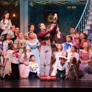 theatrical scene from the nutcracker ballet in las vegas with children in period costumes and nutcracker doll held high at smith center