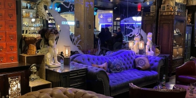 eclectic speakeasy lounge at the lock in las vegas with velvet seating vintage decor and warm lighting inside cabinet of curiosities