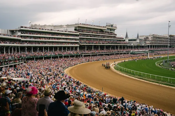 racehorses rounding the track with packed grandstands