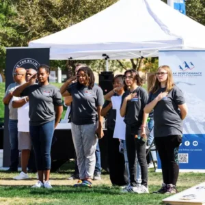 group of people with hands over hearts at vetfest in downtown summerlin las vegas with tents banners and cornhole game