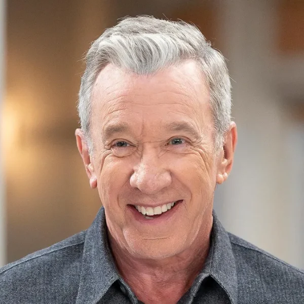 Smiling portrait of Tim Allen in a dark collared shirt with warm indoor lighting and soft background