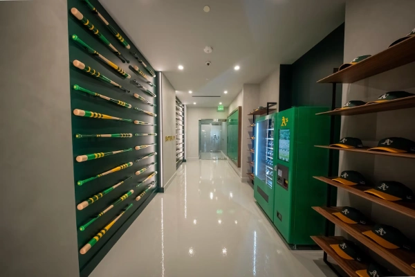 Hallway at As Las Vegas preview center featuring bat grid wall, cap display, and branded vending machine