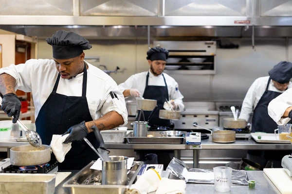 Culinary students practicing cooking skills in a Las Vegas training kitchen at the Culinary Academy