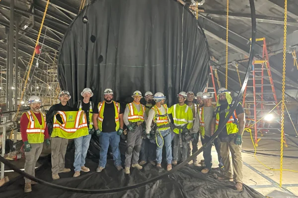Sheet metal workers in safety gear standing inside a large industrial ventilation duct during a SMART Local 88 training session