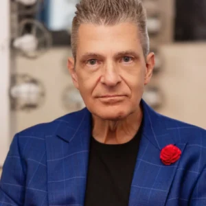 Portrait of Dr. Scott Bonn in a blue checkered blazer with red rose pin, backstage in Las Vegas
