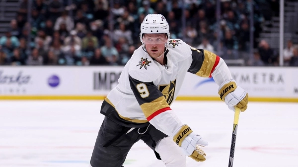 Vegas Golden Knights center Jack Eichel (number 9) on the ice during an NHL game. He is wearing the team's white away jersey with gold and black accents and a white helmet with the Golden Knights logo
