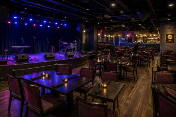 Table seating, clear aisles, stage lighting, and the intimate performance area inside Motown Extreme Theater.
