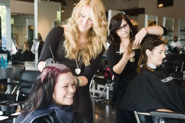 Cosmetology students styling hair in a bright salon training space at Paul Mitchell The School Las Vegas