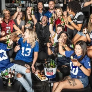 Football fans in NFL jerseys celebrating with drinks at Cabo Wabo Las Vegas during Super Bowl party