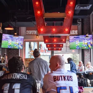 Football fans in jerseys watching Super Bowl at Las Vegas sports bar with beer and game-day energy
