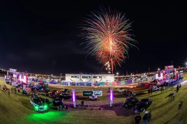 Fireworks lighting up the night sky over a classic car show at the Tacos and Tamales Festival