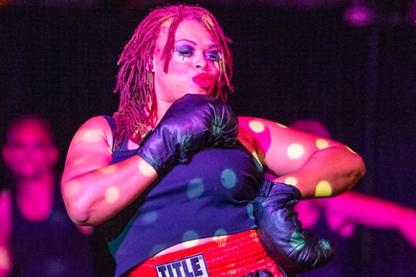 Performer in boxing attire striking a dynamic pose onstage during Circus Freaks 8: Our Showgirl Era in Las Vegas with colorful spotlight effects