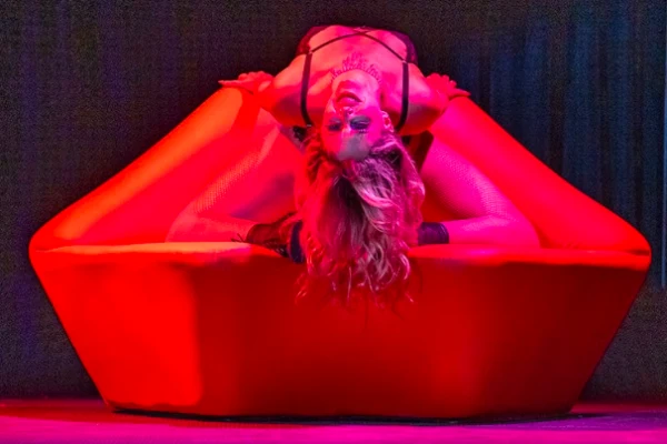 Performer posing dramatically on a bright red couch under vivid stage lighting for Circus Freaks 8: Our Showgirl Era in Las Vegas