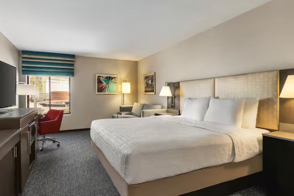 Exterior view of the Hampton Inn Tropicana in Las Vegas with palm trees, covered entrance, and mountain backdrop