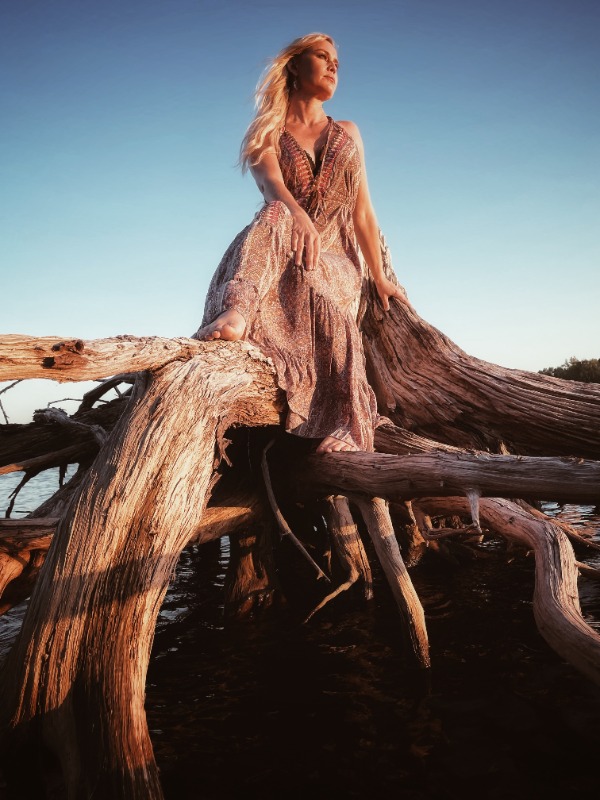 Sofia Talvik posing by driftwood during sunset for her Las Vegas folk concert series