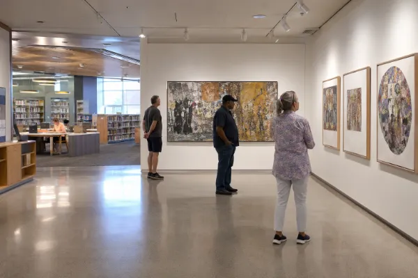 Visitors viewing contemporary artwork in a gallery inside Sahara West Library.