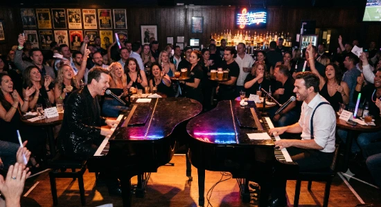 A photo of a free dueling piano show in Las Vegas featuring a low‑lit, high‑energy piano bar packed with people.