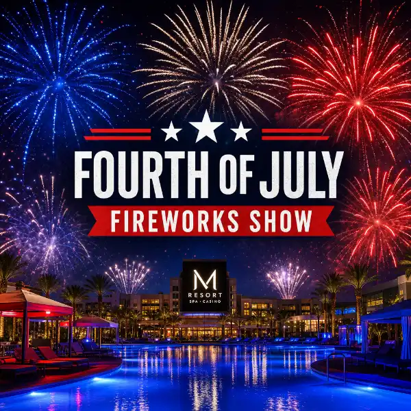 **Alt Text:** Fireworks burst in red, white, and blue above the illuminated pool deck at M Resort Spa Casino in Henderson, Nevada, celebrating Independence Day with reflections shimmering on the water and the resort’s logo centered in view.