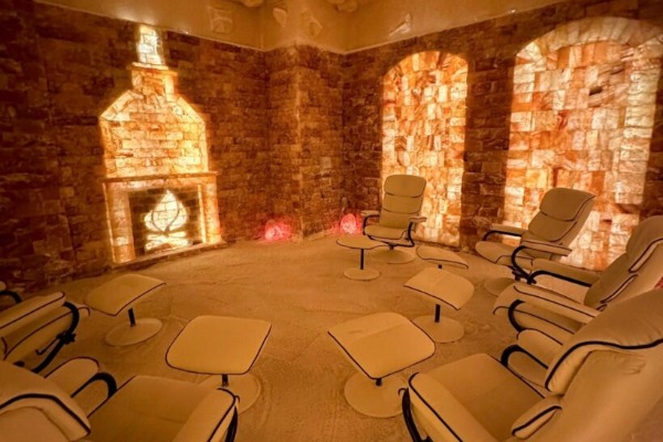 An ambient, orange-glowing wellness cave lined completely with therapeutic Himalayan salt bricks and zero-gravity recliners at The Salt Room LV