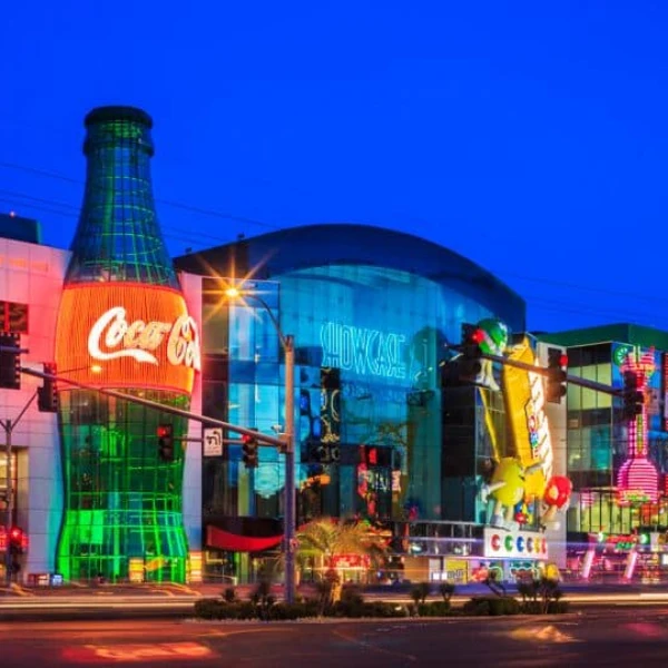 A street view of the Showcase Mall in Las Vegas featuring a 100-foot-tall Coke bottle and a giant M&Ms sign