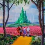 The four main Wizard of OZ characters Dorothy, the Tin Man, the Scarecrow, and the Cowardly Lion stroll down the Yellow Brick Road toward the Emerald City