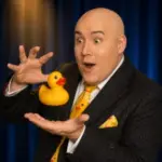Adam London reacts playfully as a yellow rubber duck levitates between his hands during Laughternoon.