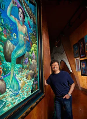 Artist Wil Cormier with mermaid-themed artwork displayed at Silverton.