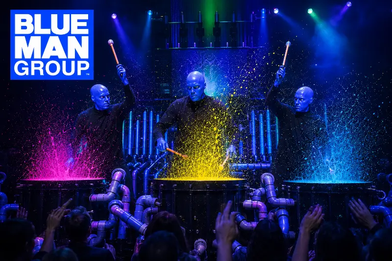 Three Blue Man Group performers create colorful paint explosions while playing an elaborate percussion stage in Las Vegas.