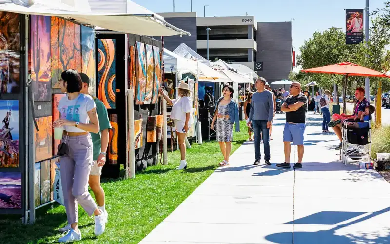 Attendees of the Downtown Summerlin Festival of Arts browse through galleries in an outdoor park area.