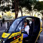 A woman drive an electric three-wheeled car past the Bellagio Fountains while on an Electric Vegas FUV fun utility vehicle tour in Las Vegas.