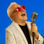 Elton John tribute performer singing into a microphone.