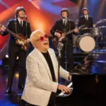 An Elton John tribute pianist in red star glasses performs with four Beatles tribute musicians onstage in Las Vegas.