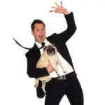 Farrell Dillon performing onstage holding a Pug dog.
