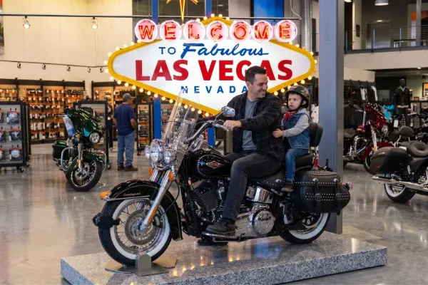 Visitor posing for a photograph on a Harley-Davidson display motorcycle in Las Vegas