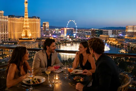 Group of friends enjoying luxury rooftop dining and cocktails overlooking the lit-up Las Vegas Strip skyline at dusk.