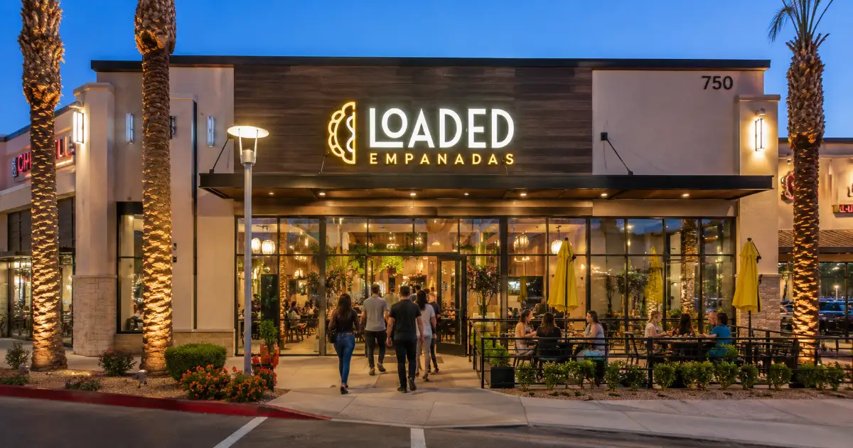 The permanent sign, glass entrance, and patio identify Loaded Empanadas at Boca Park in west Las Vegas.