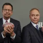 Penn & Teller performing a card trick on stage in their magic show.