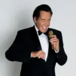 Wayne Newton singing into a microphone.