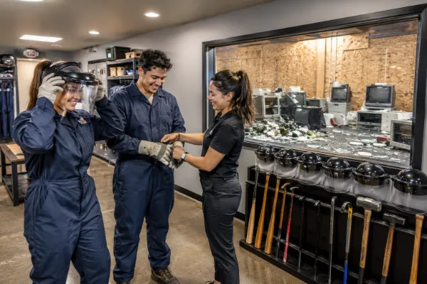 Staff member helps guests put on protective safety gear before a Wreck Room Las Vegas rage room experience.