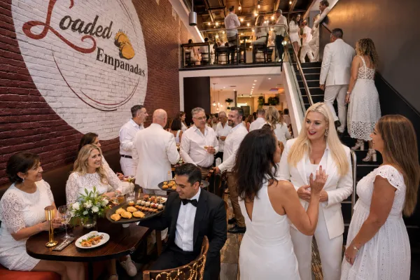 Guests in elegant white attire mingle inside Loaded Empanadas during Yvette Auger’s White Dress Soiree in Las Vegas.
