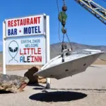 A flying saucer hovers next to a sign for a restaurant in Rachel Nevada near Area 51.